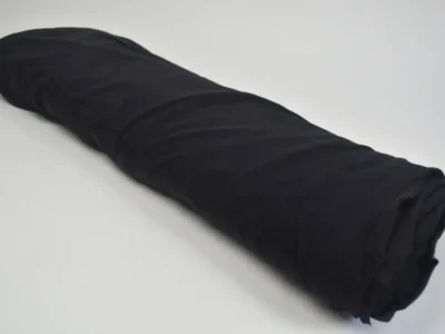 bolt of black cotton jersey spandex fabric on white background